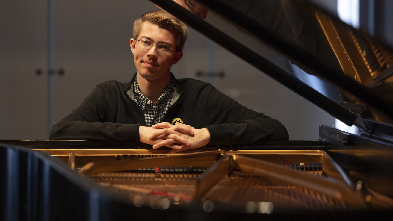 student at piano looking into camera smiling